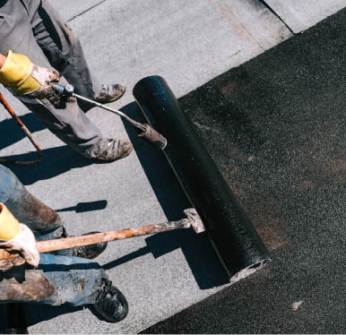 Construction workers installing bituminous membrane waterproofing system insulation with blowtorch