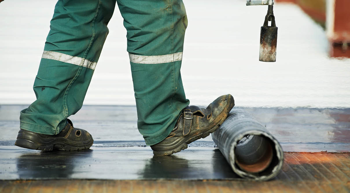 Roofer installing Roofing felt with heating and melting of bitumen roll by torch on flame during roof repair