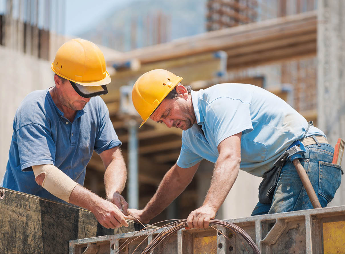 Authentic construction workers collaborating in the installation of cement formwork frames